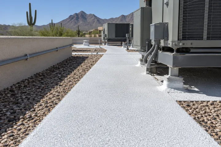 Fresh white coating with granules on a walkway path near rooftop equipment