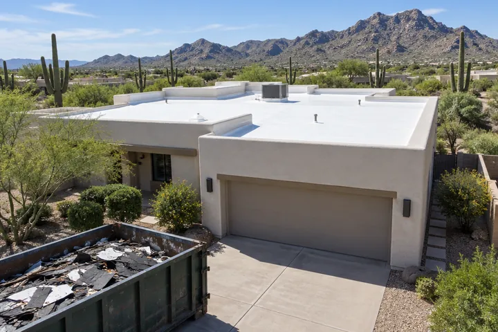 Finished new white flat roof on a Scottsdale home with old roofing debris hauled off in a dumpster